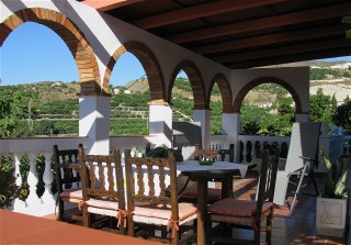 Auf der berdachten Terrasse gibt es einen stabile Holztisch