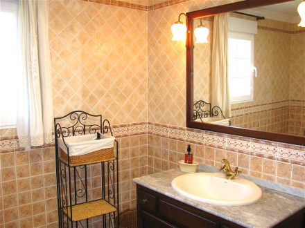 Das Bad mit Waschtisch und Badewanne ist hell und urig gefliest