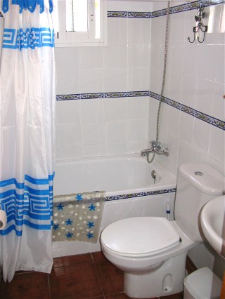 Das hell geflieste Bad hat eine Wanne, direkt unter dem kleinen Fenster.