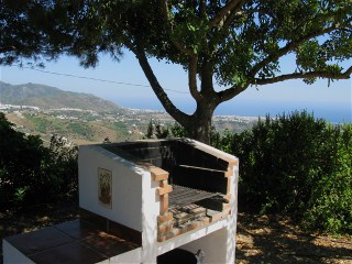 Neben der sonnigen Terrasse gibt es eine gemauerte Grillecke