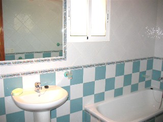 Es gibt ein blau weiss gekacheltes Bad mit Wanne